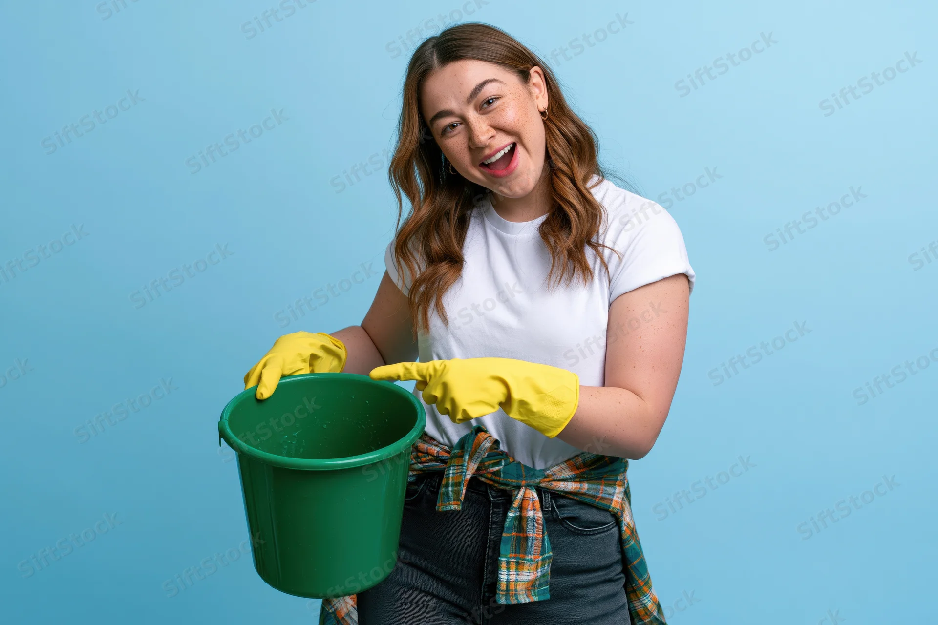 Woman smiling while holding a green bucket and wearing yellow gloves against a blue background