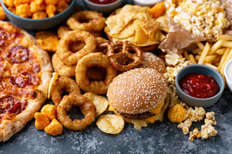 Overhead flat lay of assorted fast food and snacks spread on dark surface