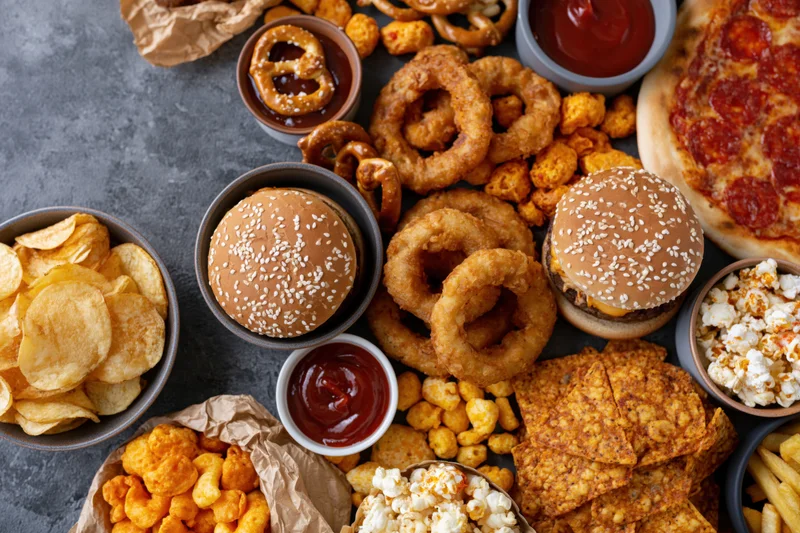 Assorted fast food and snacks arranged in a flat lay on a dark surface