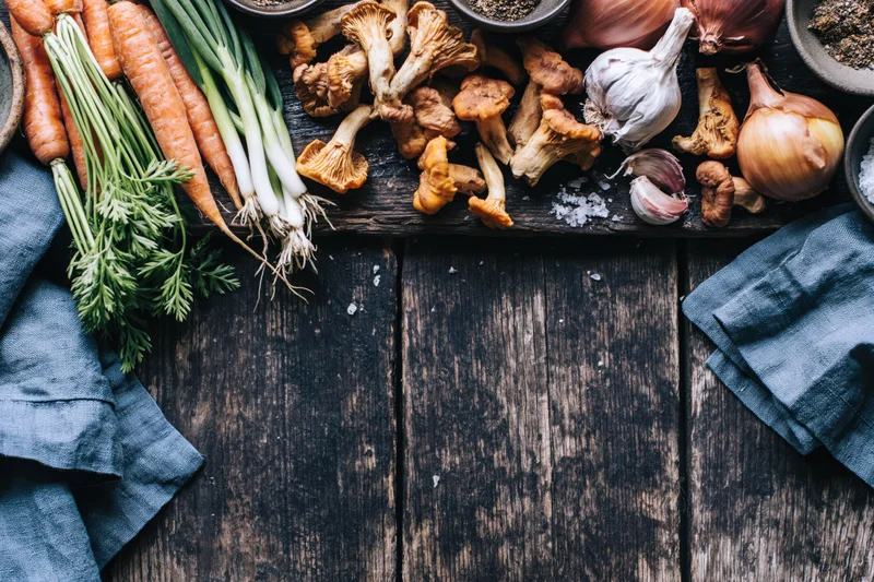 Fresh vegetables and mushrooms arranged on dark wooden table with blue cloth and copyspace below