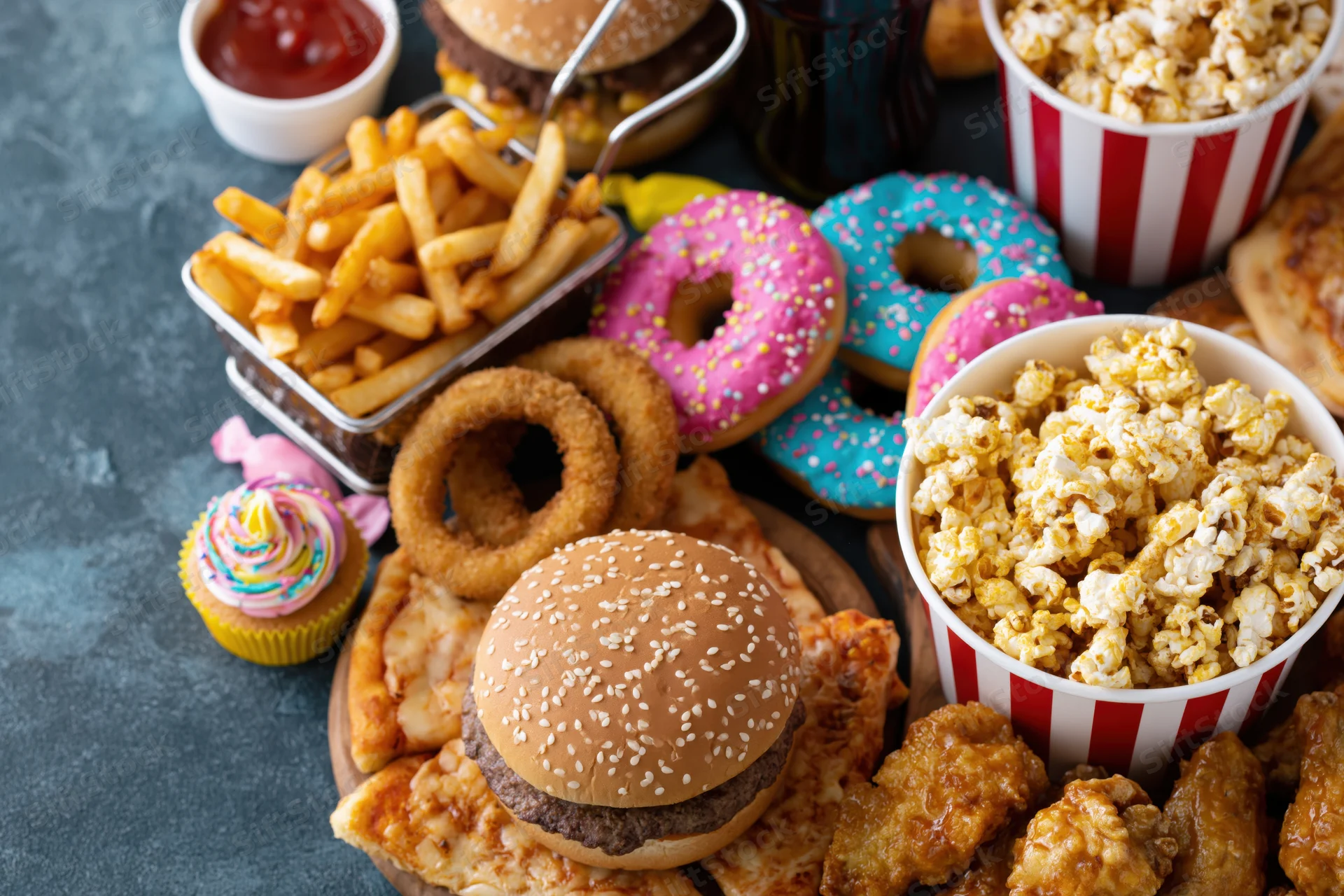 Overhead spread of assorted junk food arranged on dark surface