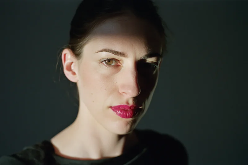 Woman with dark hair pulled back and bright pink lips in studio lighting