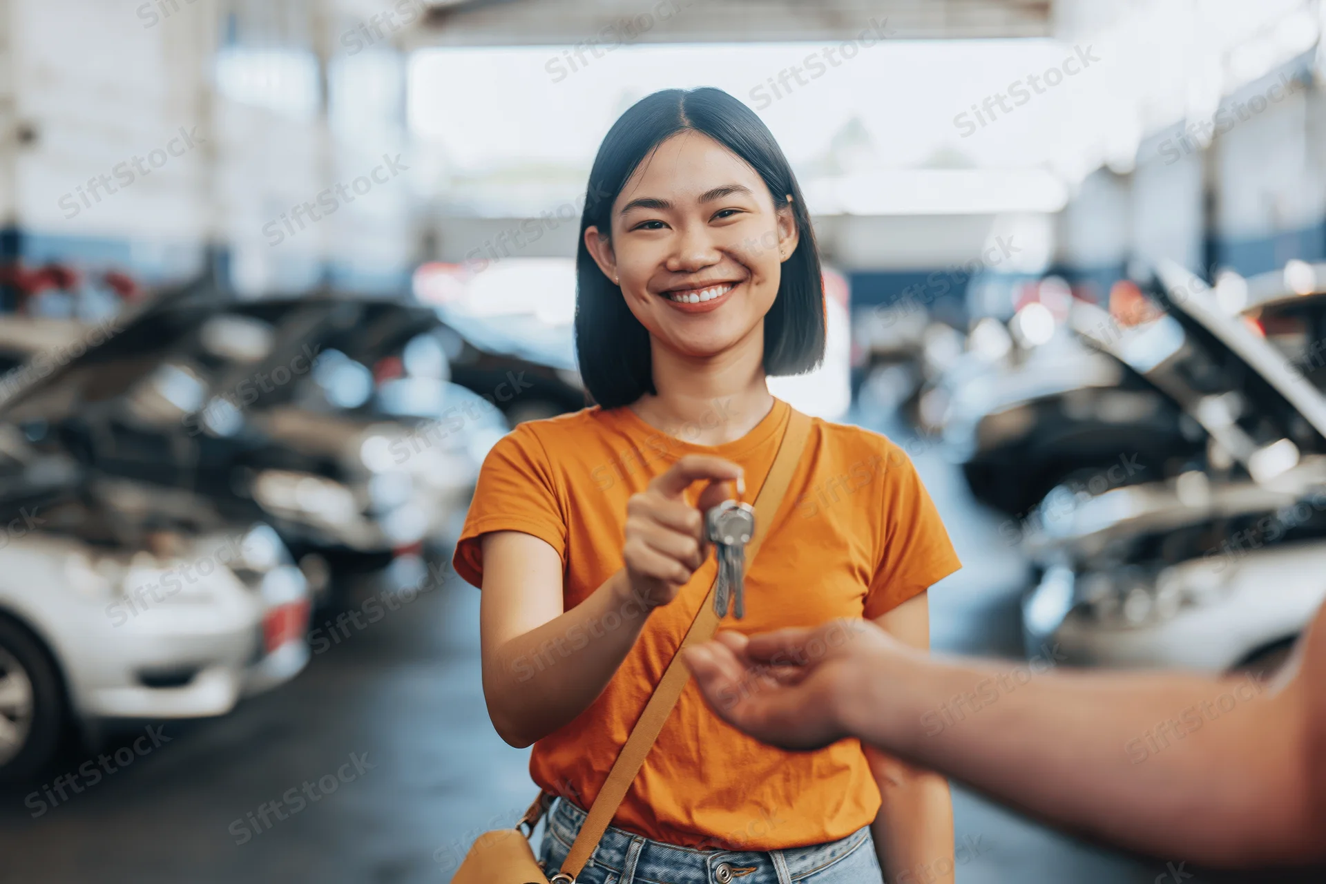 Young asian woman smiling while receiving car keys in a garage