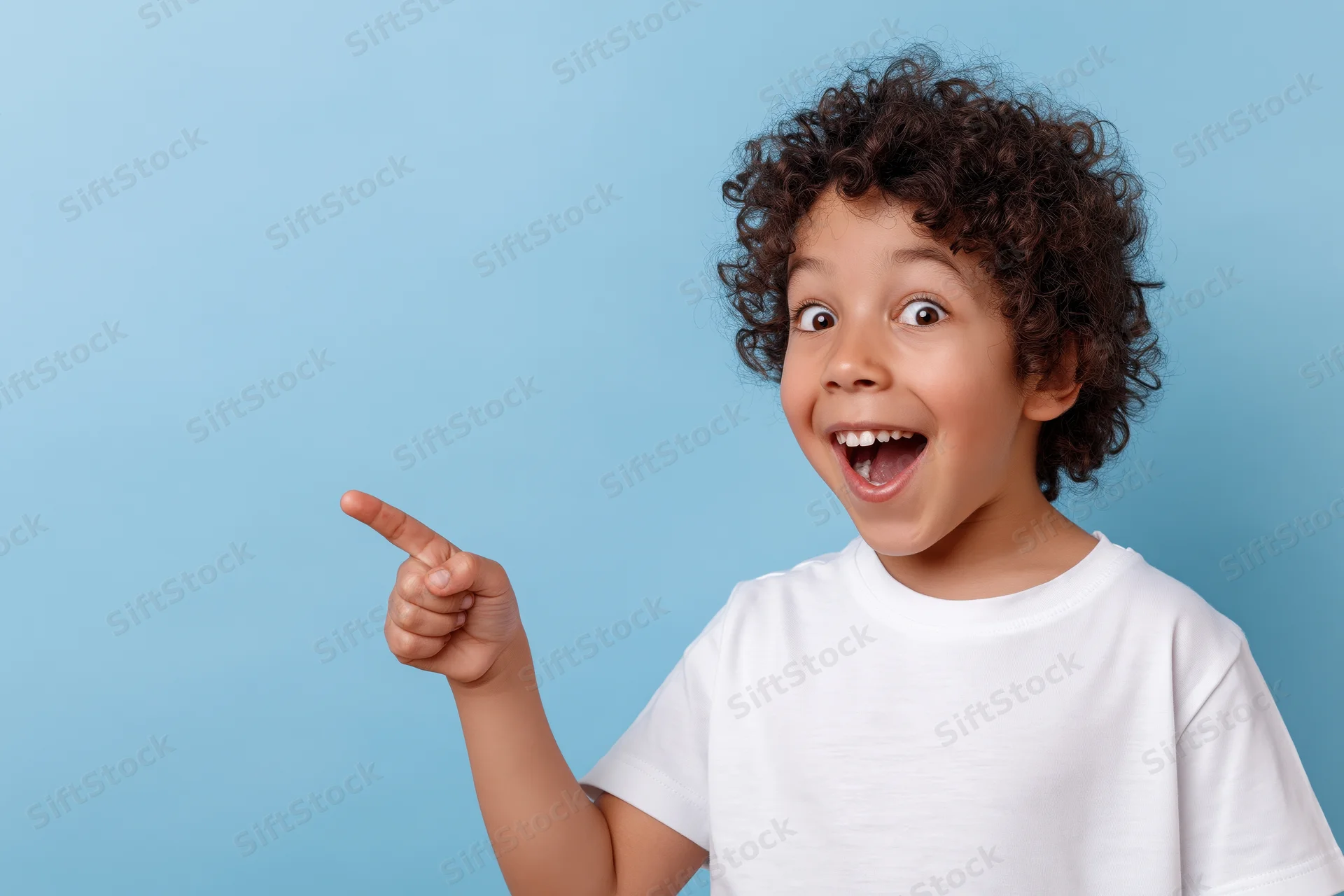 Young boy with curly dark hair pointing excitedly against blue background