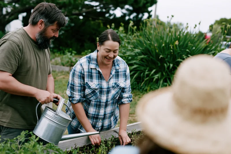 Woman and man tending plants in a raised garden bed outdoors