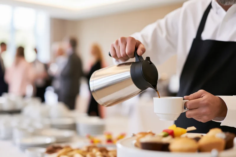 Waiter pouring coffee into a cup at a breakfast buffet during a corporate event