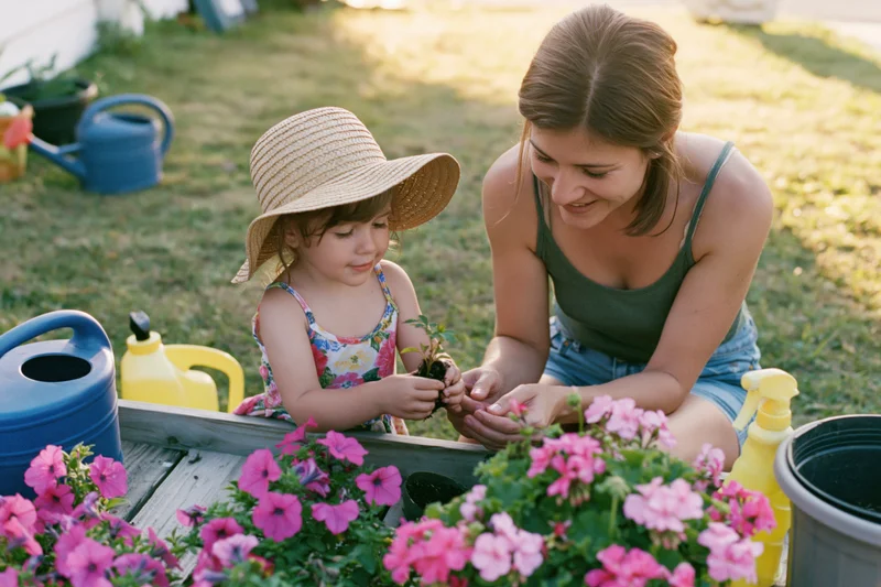 Mother and daughter planting flowers together in a garden bed