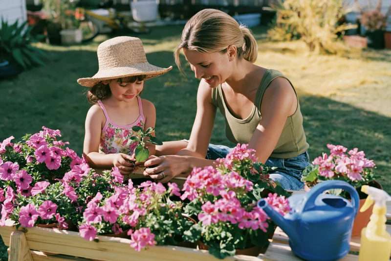 Mother and daughter planting flowers together in a garden bed on a sunny day