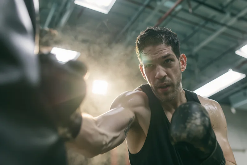 Muscular male boxer throwing a straight punch in a gym