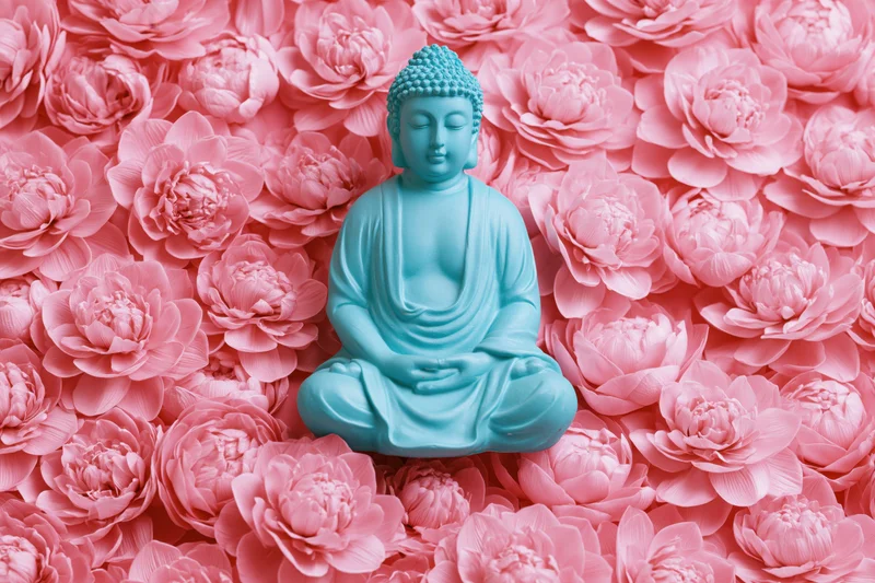 Turquoise buddha statue in seated meditation pose surrounded by pink lotus flowers