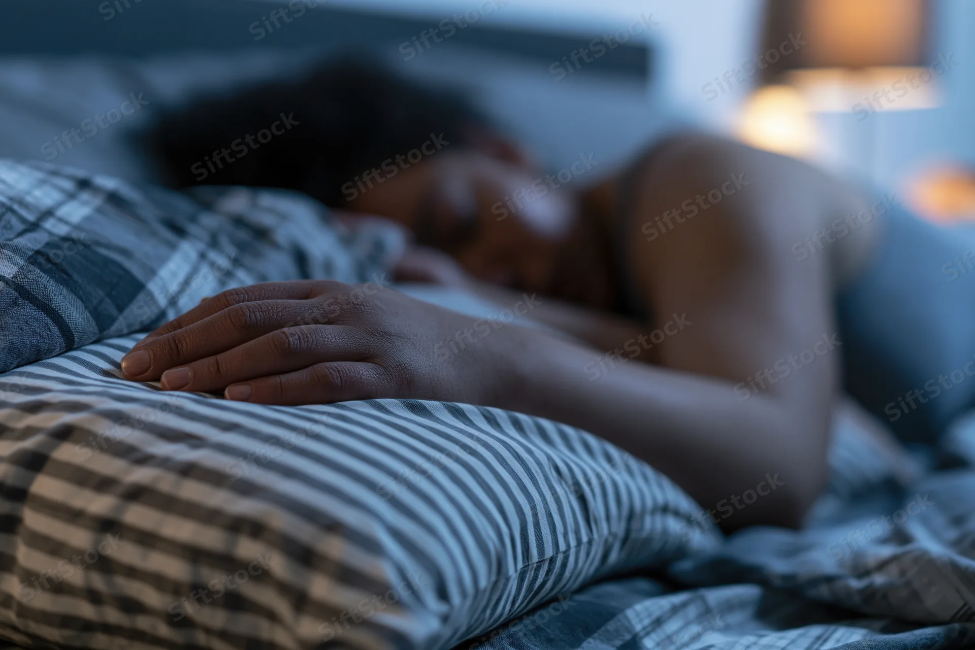 Woman sleeping peacefully in bed at night with hand resting on pillow