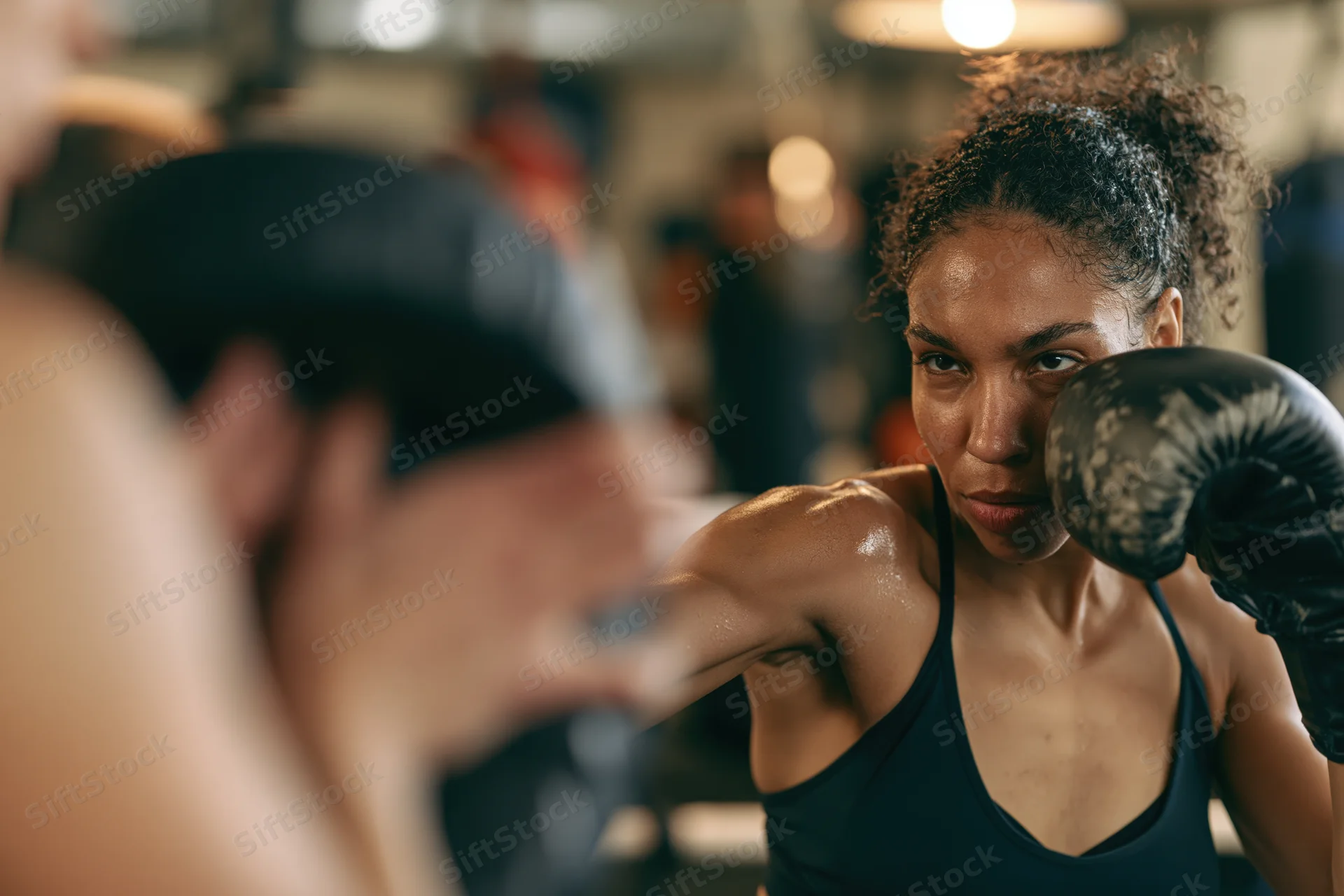 Young black woman boxer throwing a focused jab during training in a gym