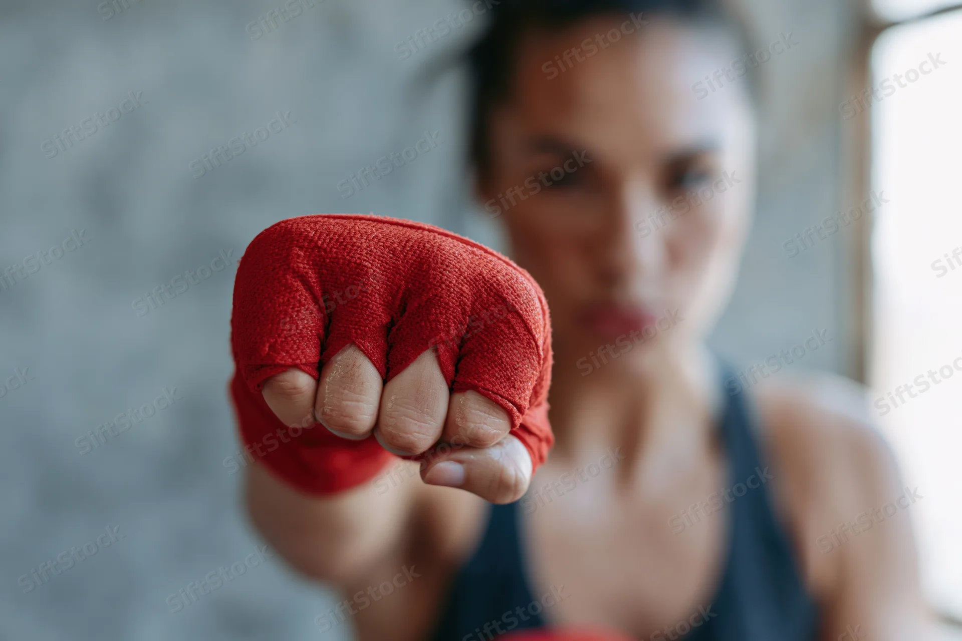 Woman boxer throwing a straight punch toward the camera in a gym