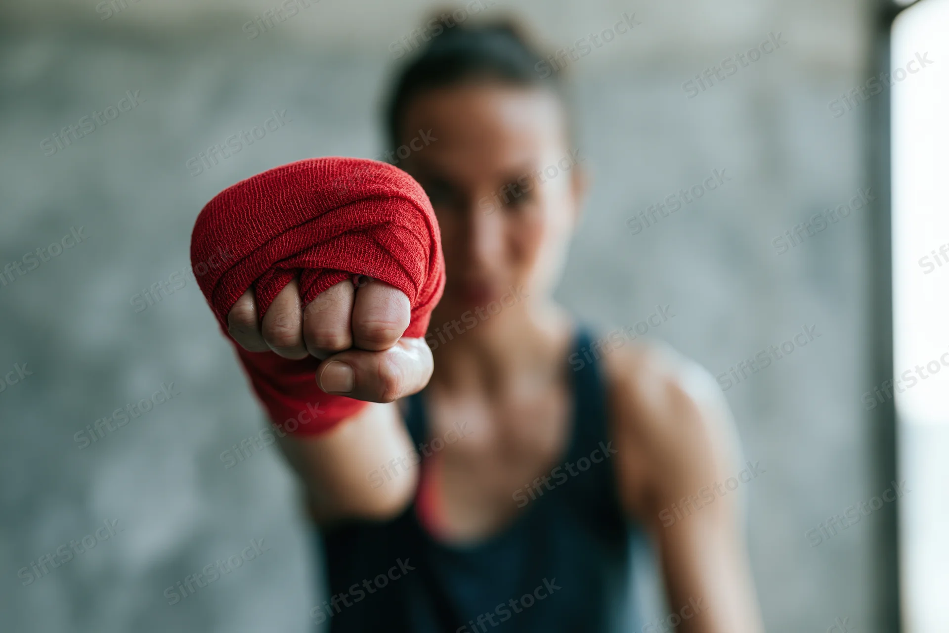 Young woman boxer throwing a straight punch toward the camera in a gym