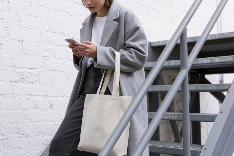 Woman checking smartphone while standing on metal staircase outdoors