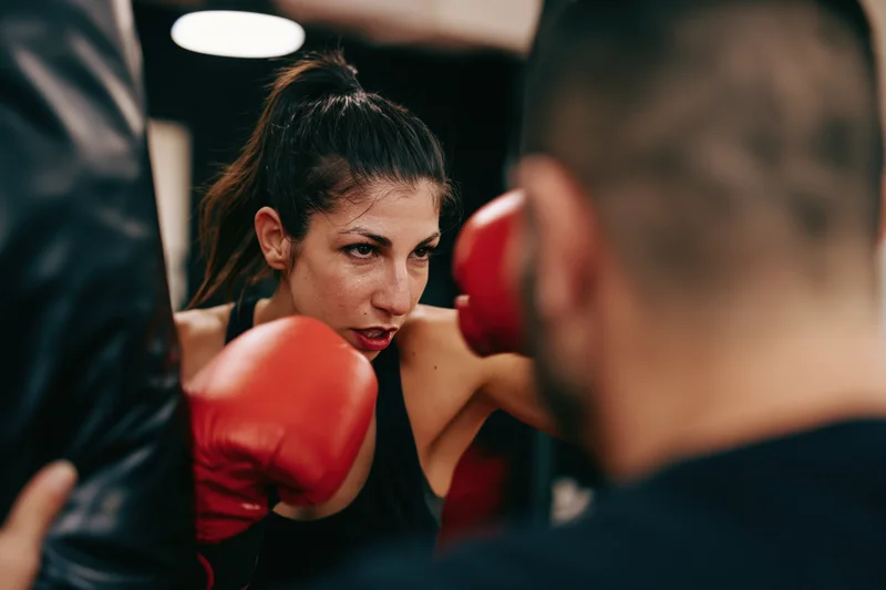 Woman in red boxing gloves training with coach in gym