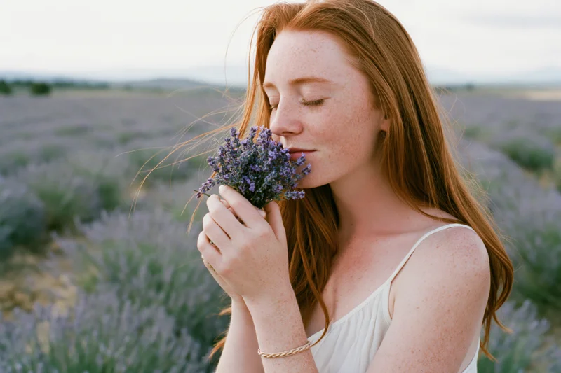 Woman smelling a small bouquet of lavender in a field