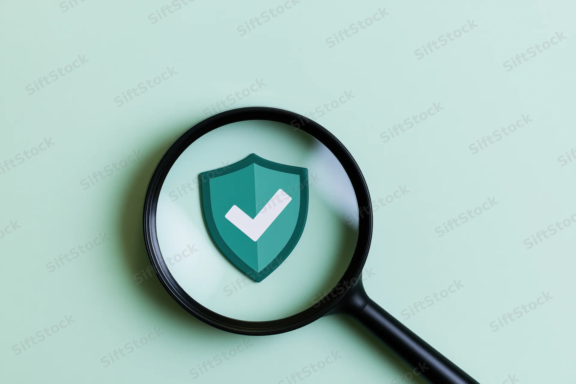 Magnifying glass over a green shield with white checkmark on mint surface