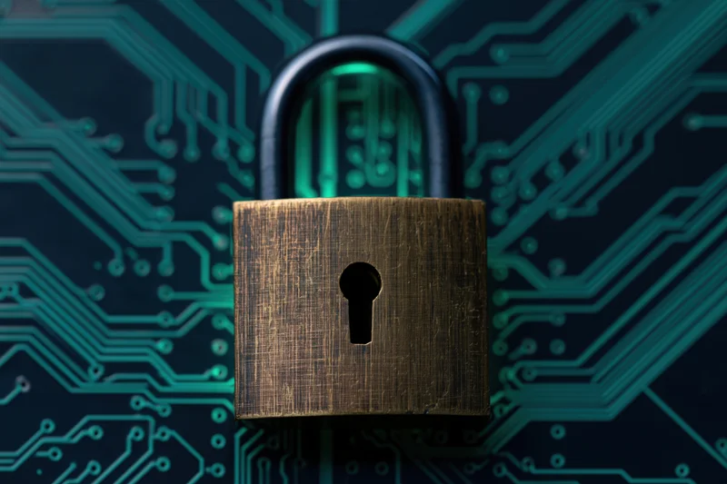 Brass padlock centered on dark circuit board with glowing teal pathways