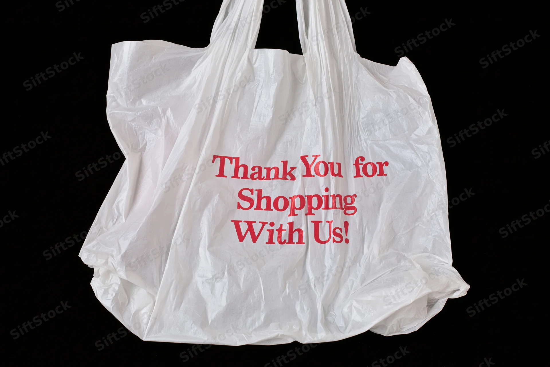 Crinkled white plastic shopping bag with red thank you message on black background