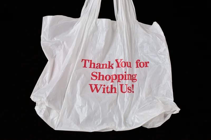 Crinkled white plastic shopping bag with red thank you message on black background