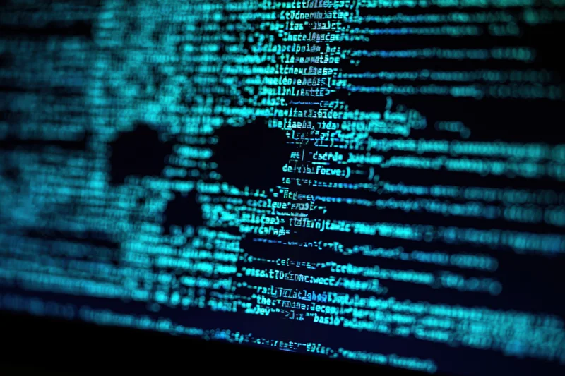 Glowing blue lines of code on a dark computer screen forming a digital world map