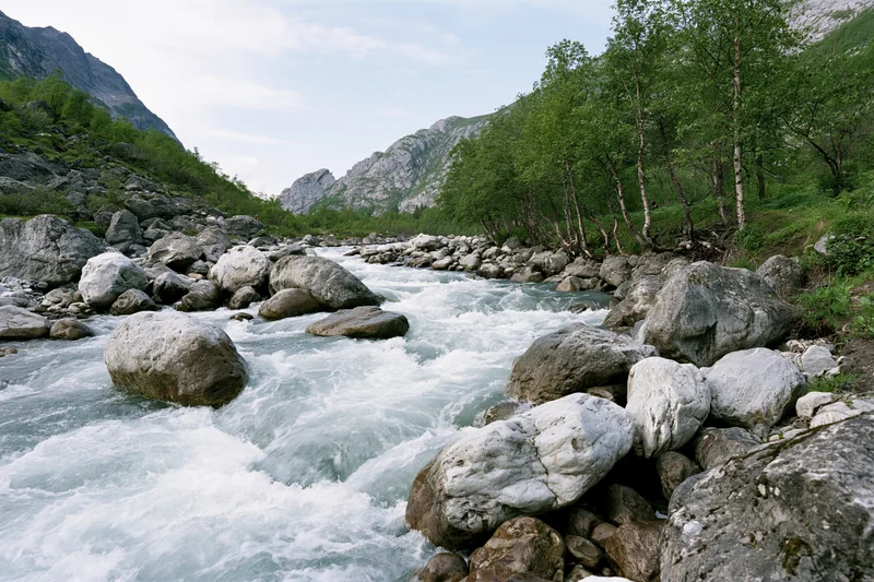 Fast-moving glacial river rushing over rounded boulders in a mountain valley