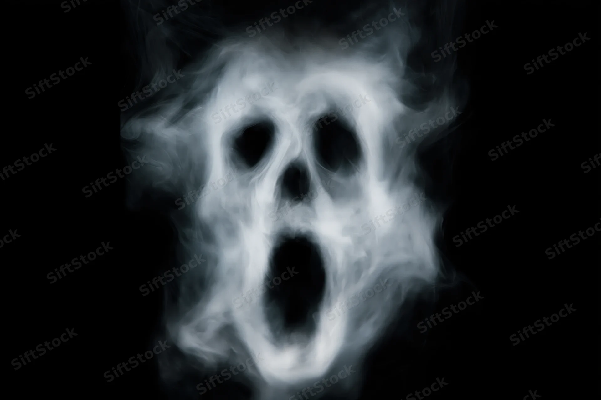 Ghostly skull formed from swirling smoke against black background