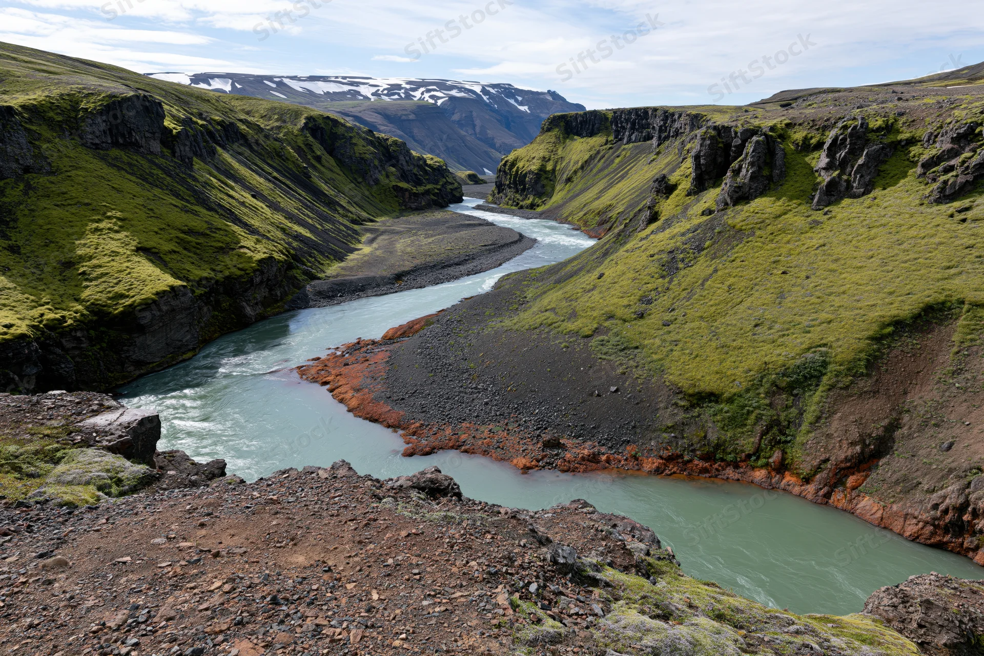 Glacial river winding through steep moss-covered canyon in icelandic highland landscape