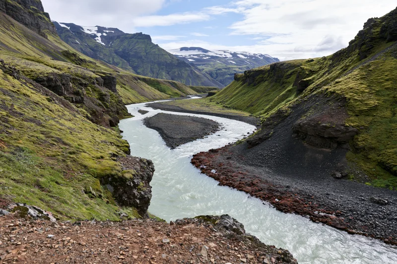 Glacial river winding through steep mossy valley in icelandic highland