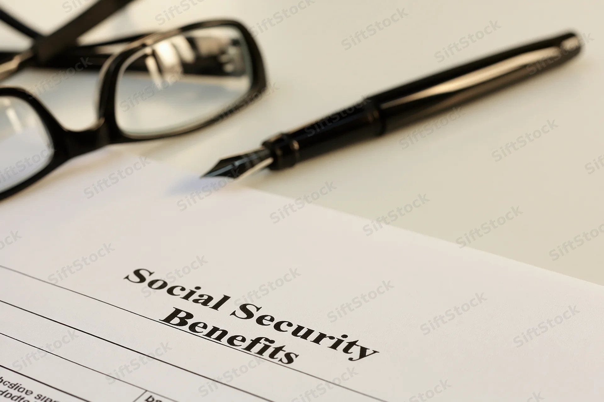 Social security benefits form on a desk with a pen and glasses nearby