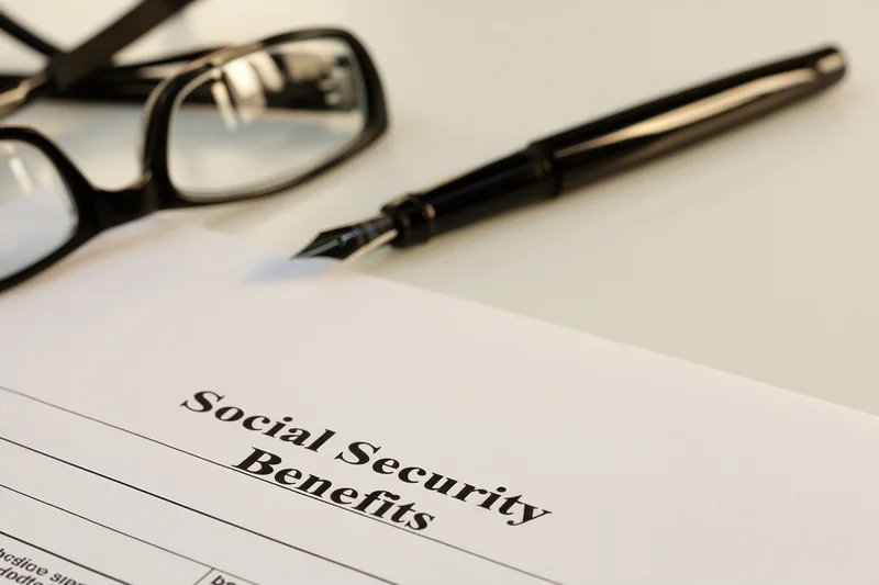 Social security benefits form on a desk with a pen and glasses nearby