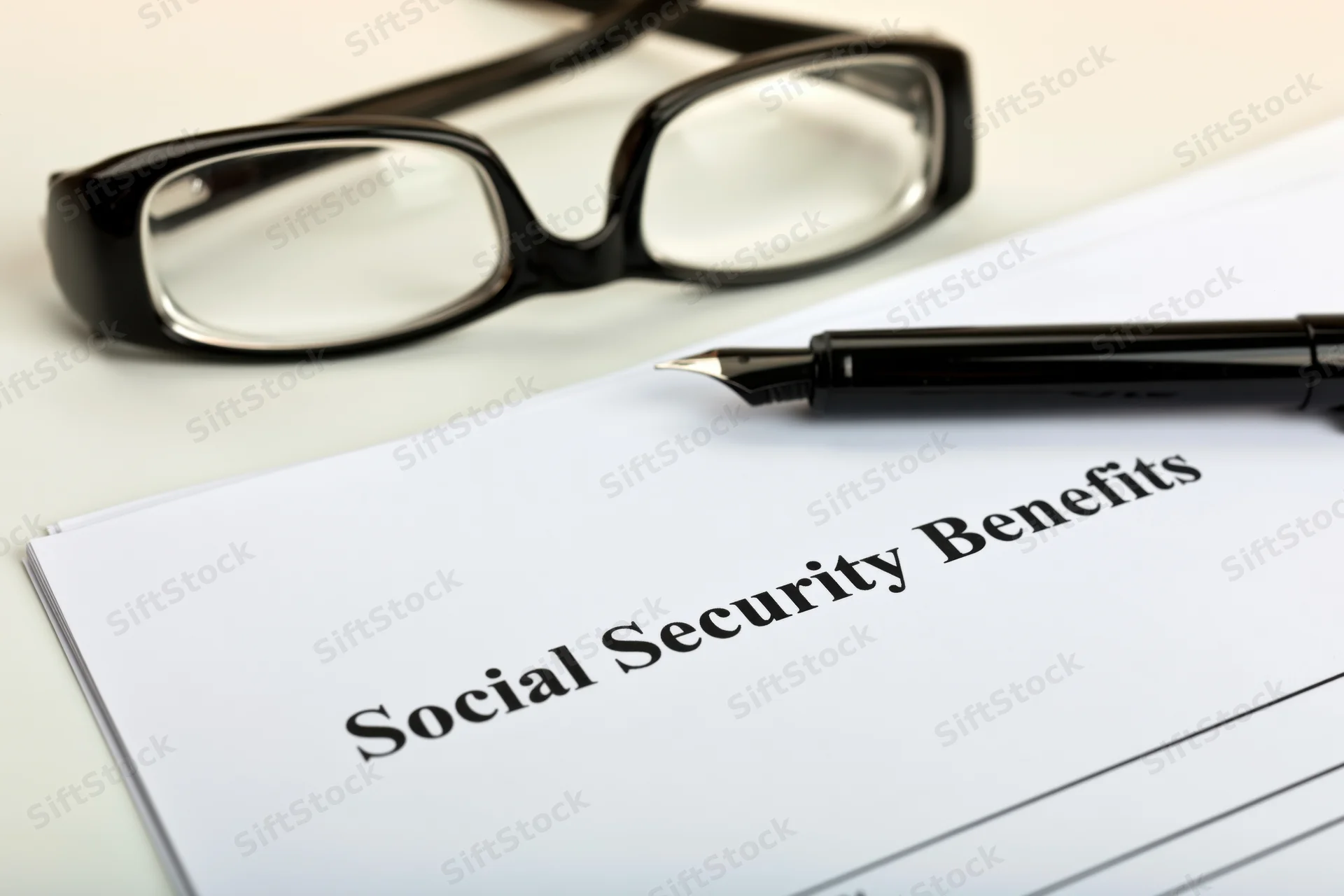 Social security benefits form on a desk with a pen and eyeglasses nearby