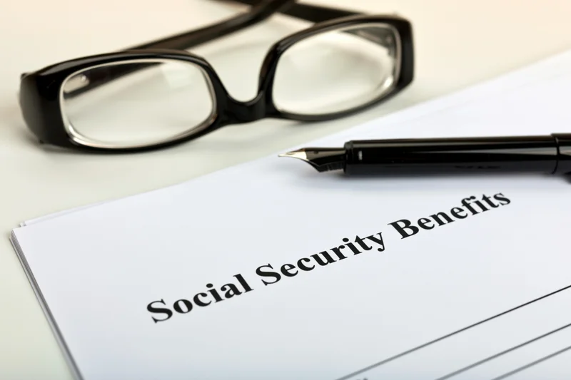 Social security benefits form on a desk with a pen and eyeglasses nearby