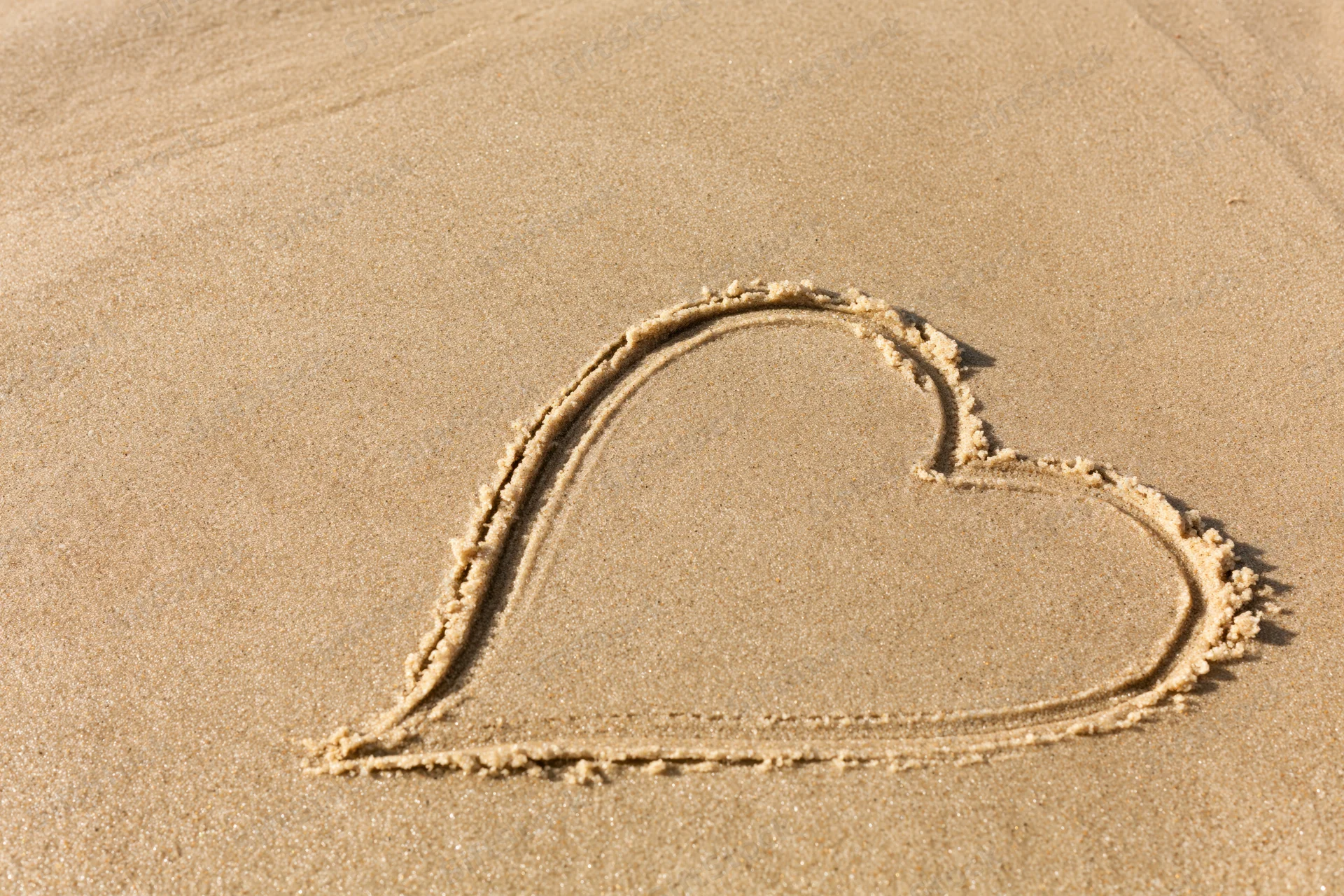 Heart shape drawn in wet sand on a beach