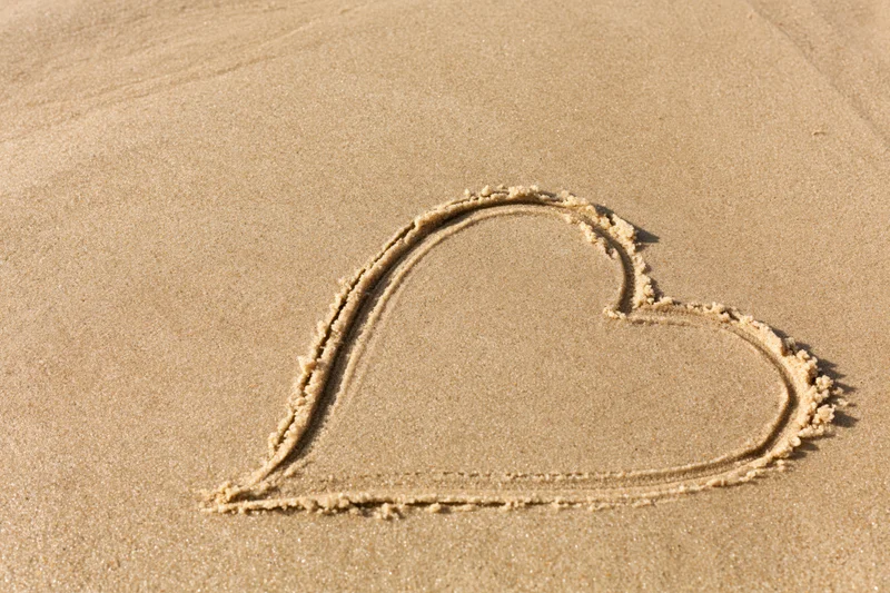 Heart shape drawn in wet sand on a beach