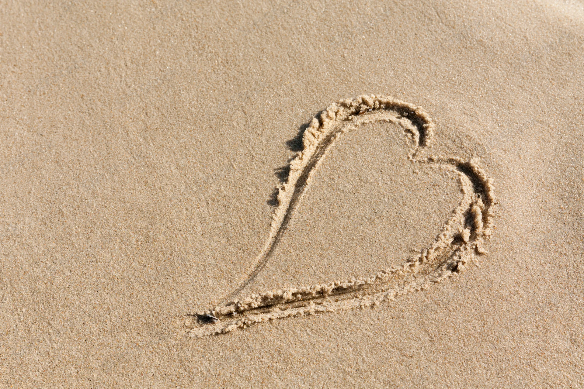 Heart shape drawn in wet sand on a beach