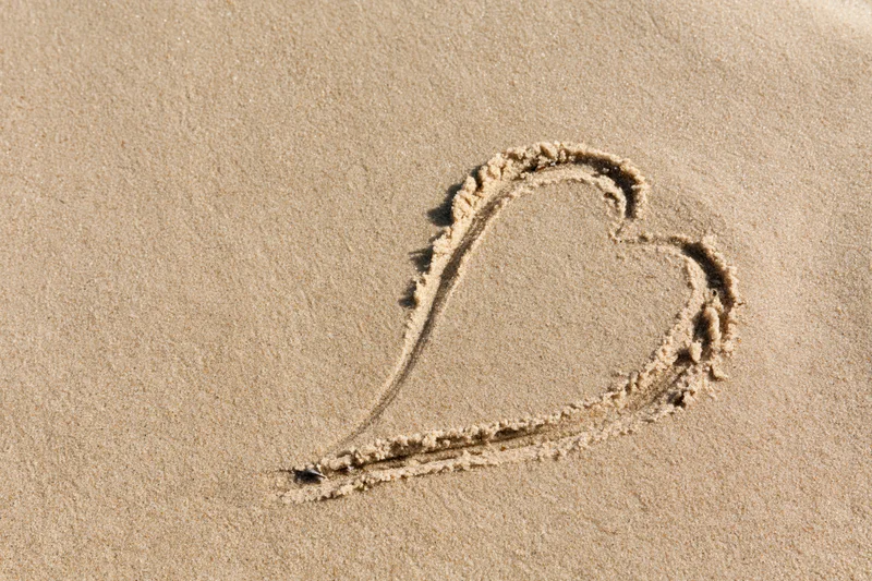Heart shape drawn in wet sand on a beach