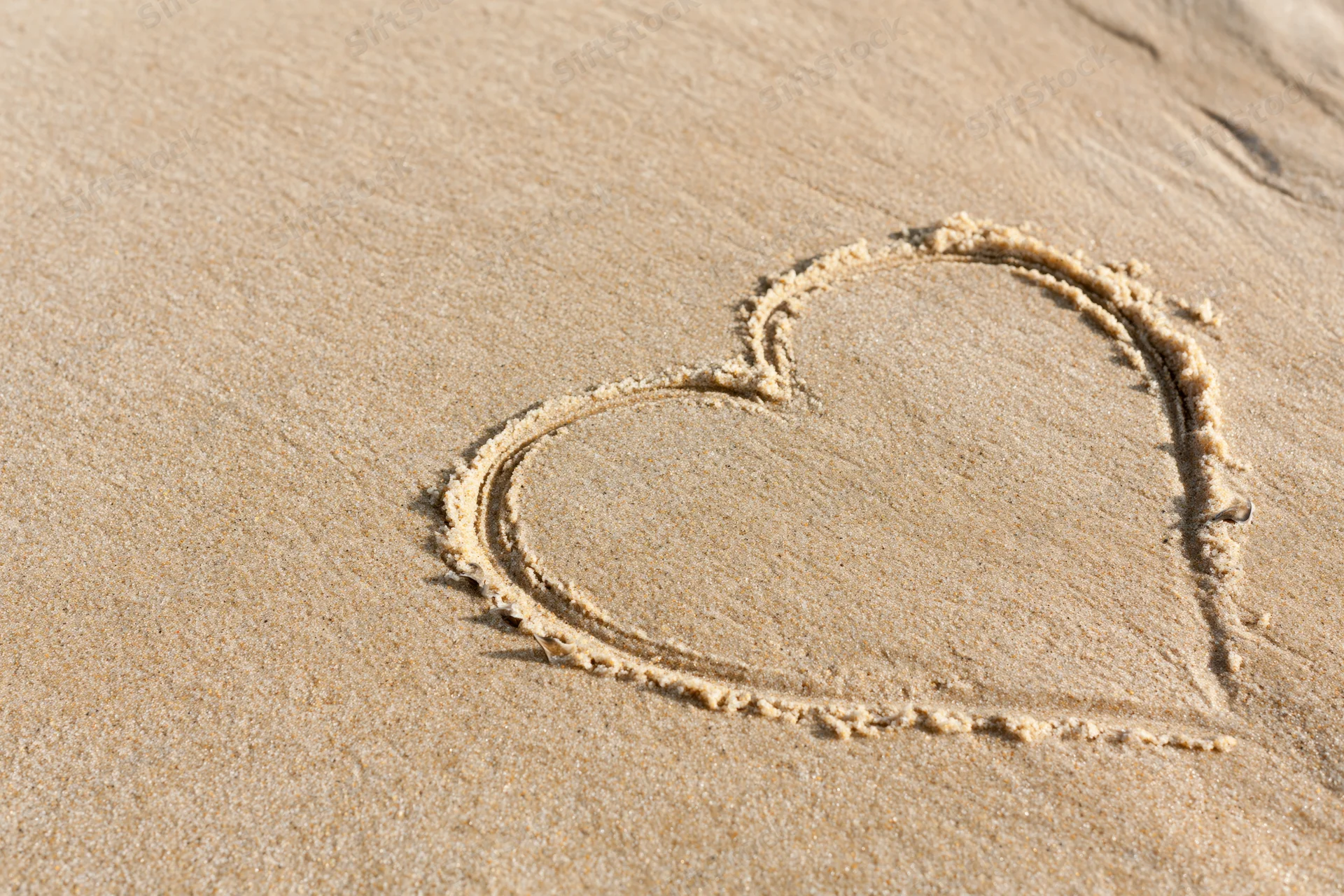 Heart shape drawn in wet sand on a beach
