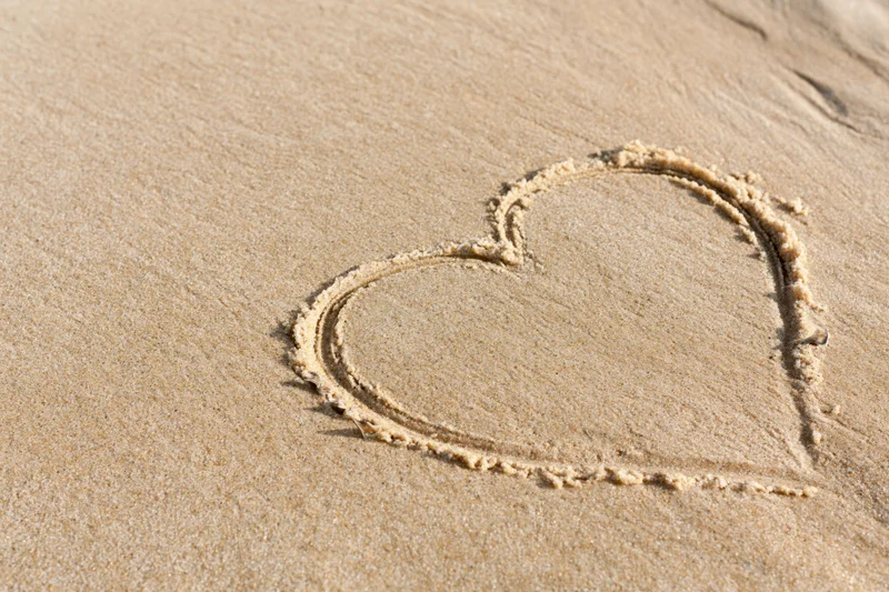 Heart shape drawn in wet sand on a beach