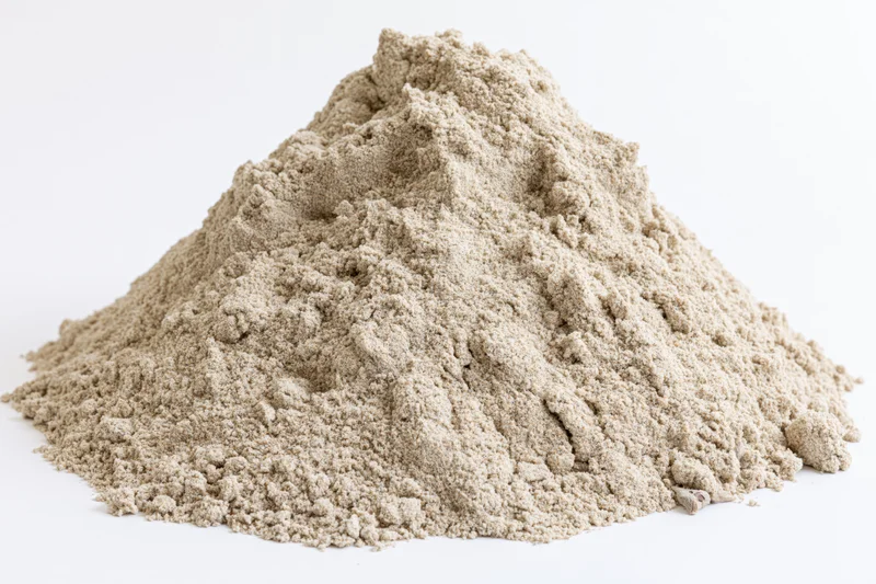 Mound of dry construction sand piled on a white surface