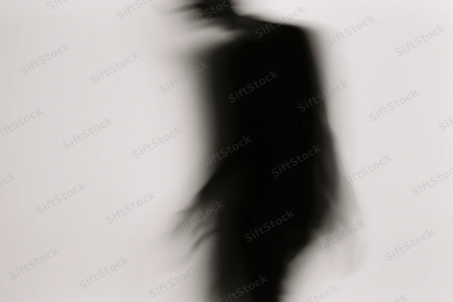 Blurred silhouette of a person in motion against a plain light background