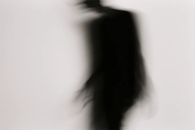 Blurred silhouette of a person in motion against a plain light background