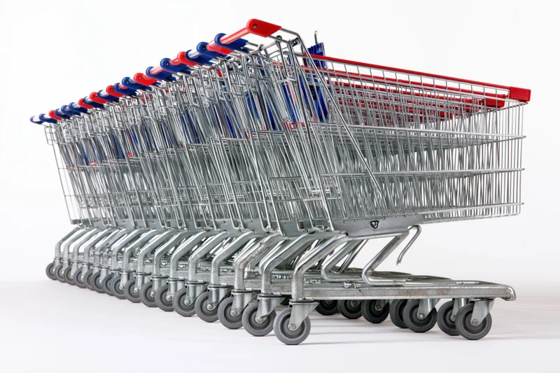 Row of nested metal supermarket shopping carts stacked in a line on white background