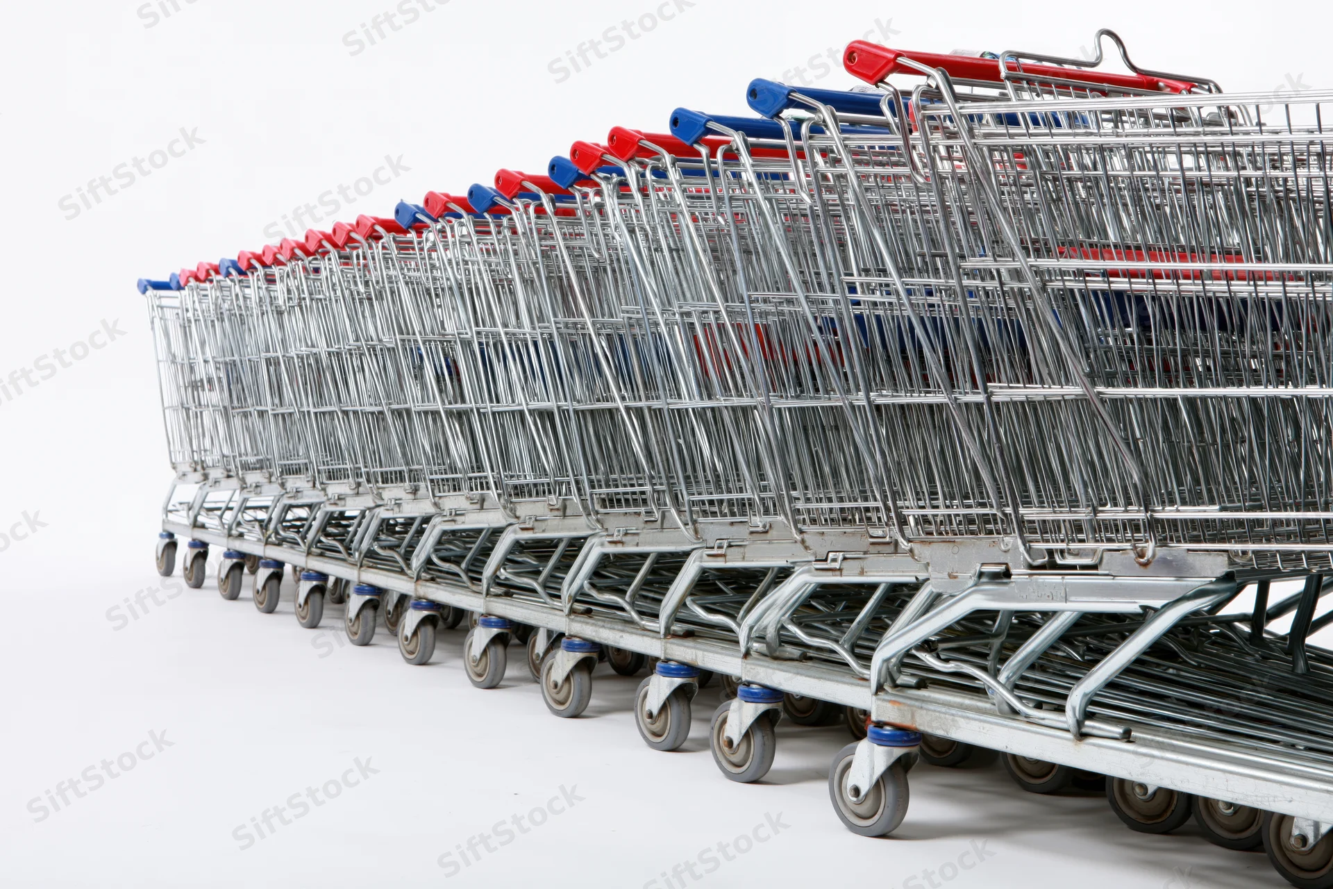 Row of nested metal supermarket shopping carts stacked in a line on white background