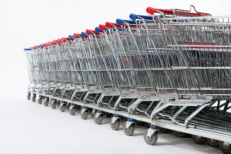 Row of nested metal supermarket shopping carts stacked in a line on white background