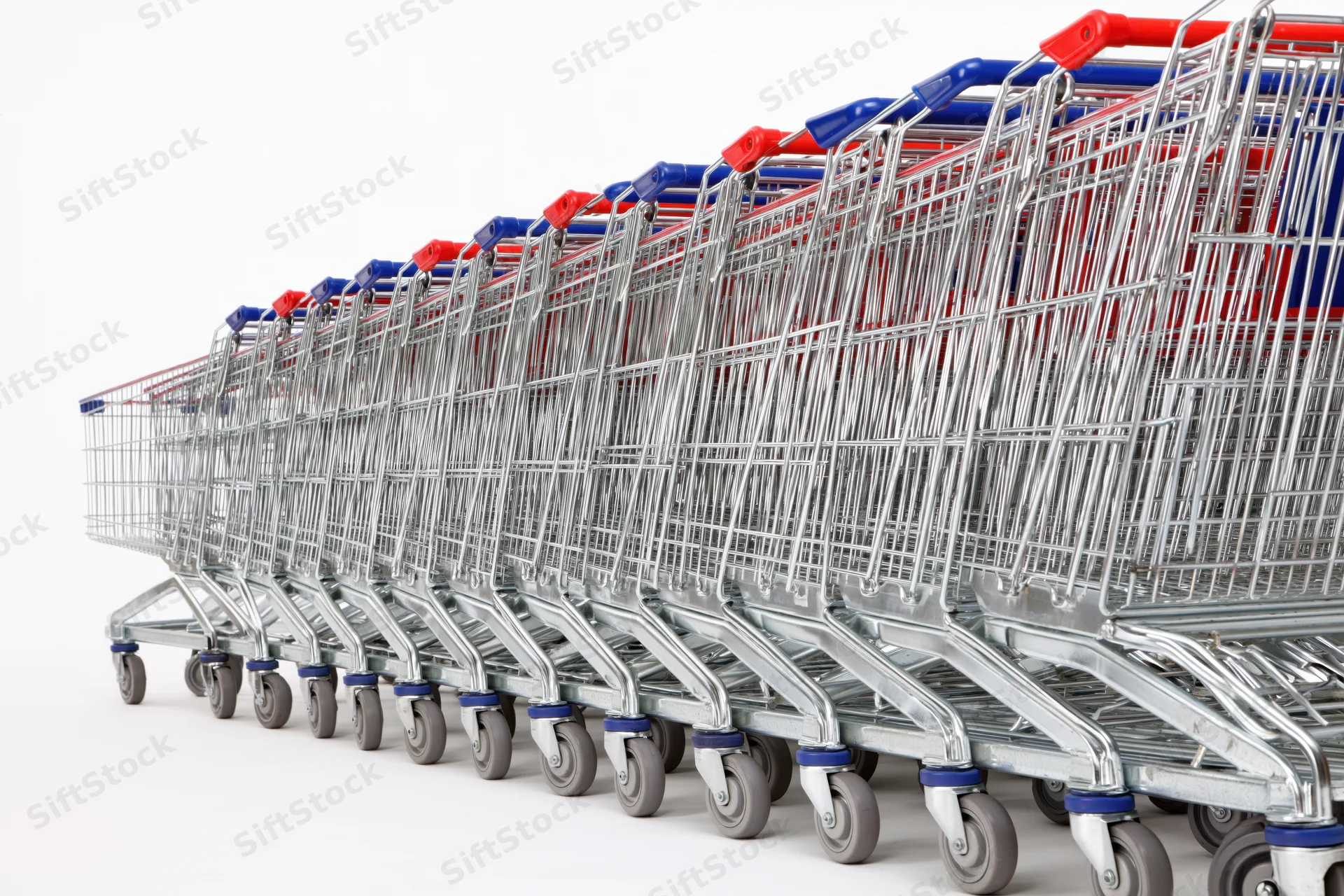 Row of metal supermarket shopping carts stacked and aligned on white background