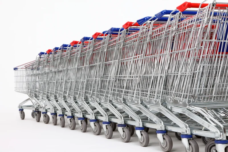 Row of metal supermarket shopping carts stacked and aligned on white background