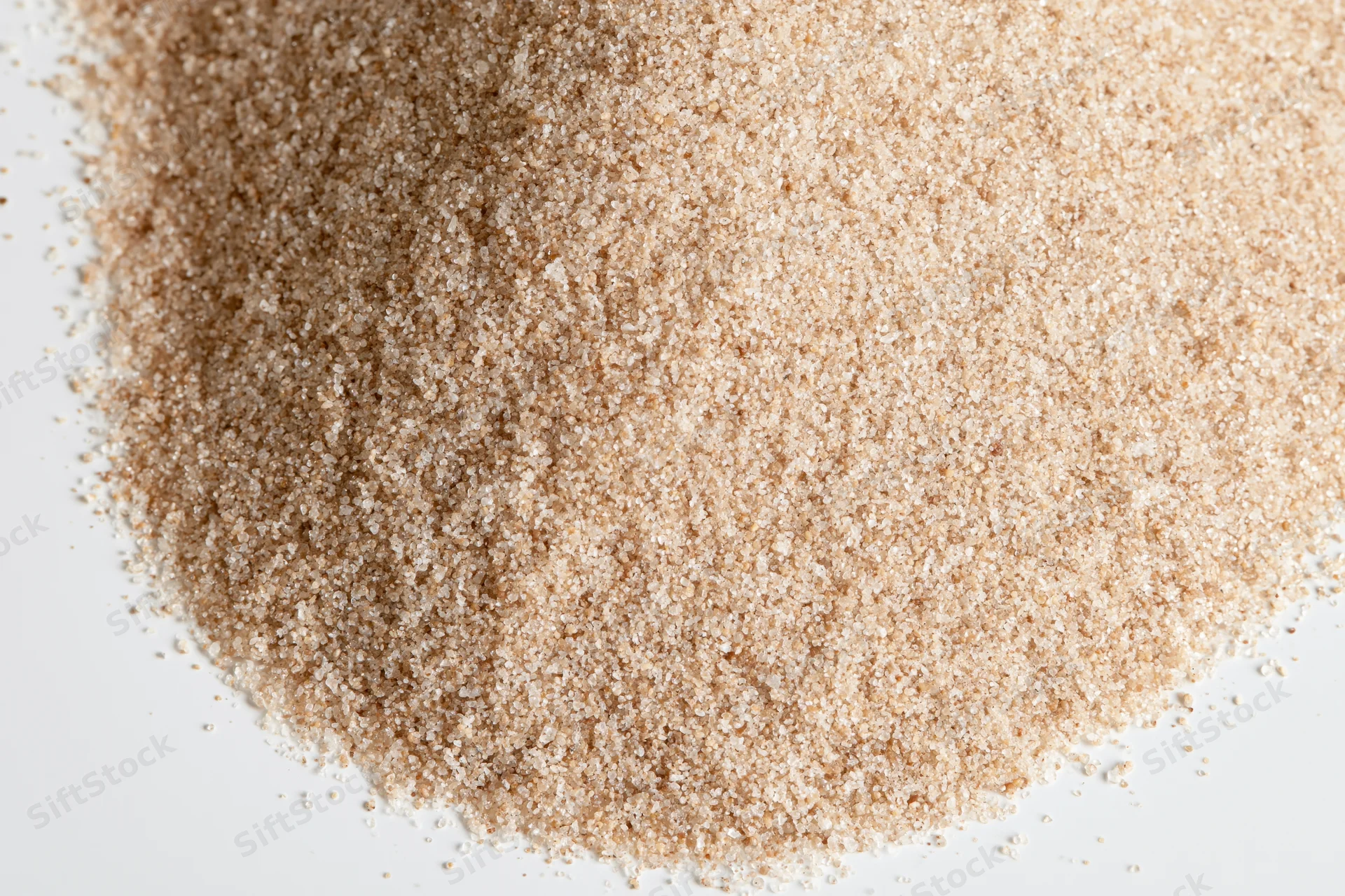 A pile of fine dry sand scattered on a white surface
