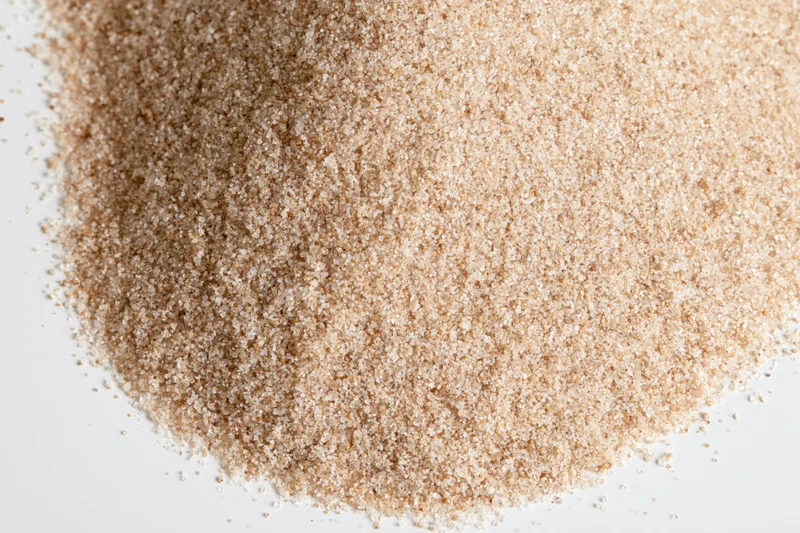 A pile of fine dry sand scattered on a white surface